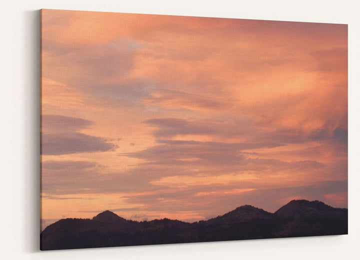 Orange and pink sunset colored clouds over Cascades mountains, Oregon